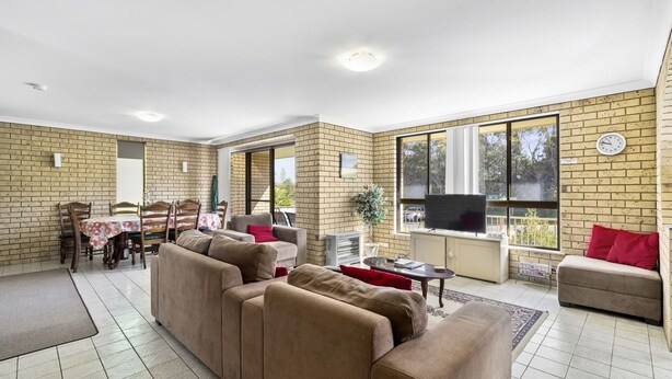 A spacious living area with a brick wall, a dining table, and a sofa. - Ocean Drift - short stroll to cafes/restaurants and beaches (Woolgoolga)