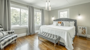 A bedroom with a large bed, a bench, a chair, and a dresser. - WALK to top Chattanooga action from this Fun Fabulous Family/Friend(ly) Home! (Chattanooga)