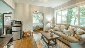 A cozy living room with a sofa, coffee table, and a kitchen area with a microwave and coffee maker. - WALK to top Chattanooga action from this Fun Fabulous Family/Friend(ly) Home! (Chattanooga)