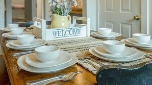 A dining table set with white bowls and plates, a welcome sign, and a vase with flowers. - WALK to top Chattanooga action from this Fun Fabulous Family/Friend(ly) Home! (Chattanooga)
