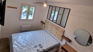 A bedroom with a bed, a bedside table, a mirror, a window, and a ceiling fan. - Apartment 400m from the sea, 26" bicycles available (Dolus-d'Oléron)