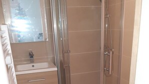 A bathroom with a glass shower enclosure, a sink with a mirror, and patterned floor tiles. - Apartment 400m from the sea, 26" bicycles available (Dolus-d'Oléron)
