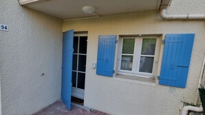 A building entrance with a door and windows, a number '94' on the wall, and a small step leading to the entrance. - Apartment 400m from the sea, 26" bicycles available (Dolus-d'Oléron)