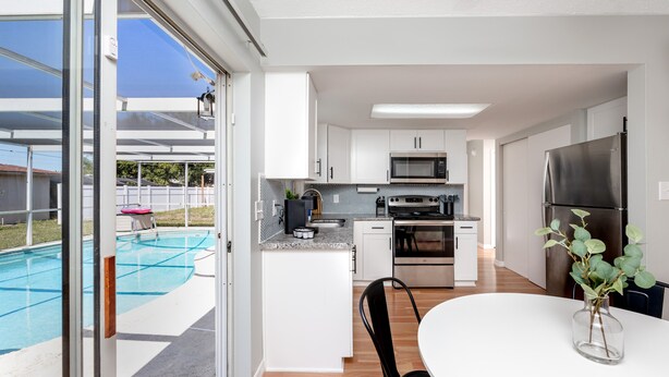 Cozinha moderna com área de jantar, piscina e vista para o exterior.