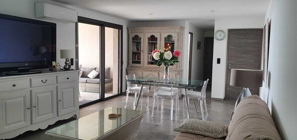 A modern living room with a glass coffee table, a sofa, and a TV on a cabinet.