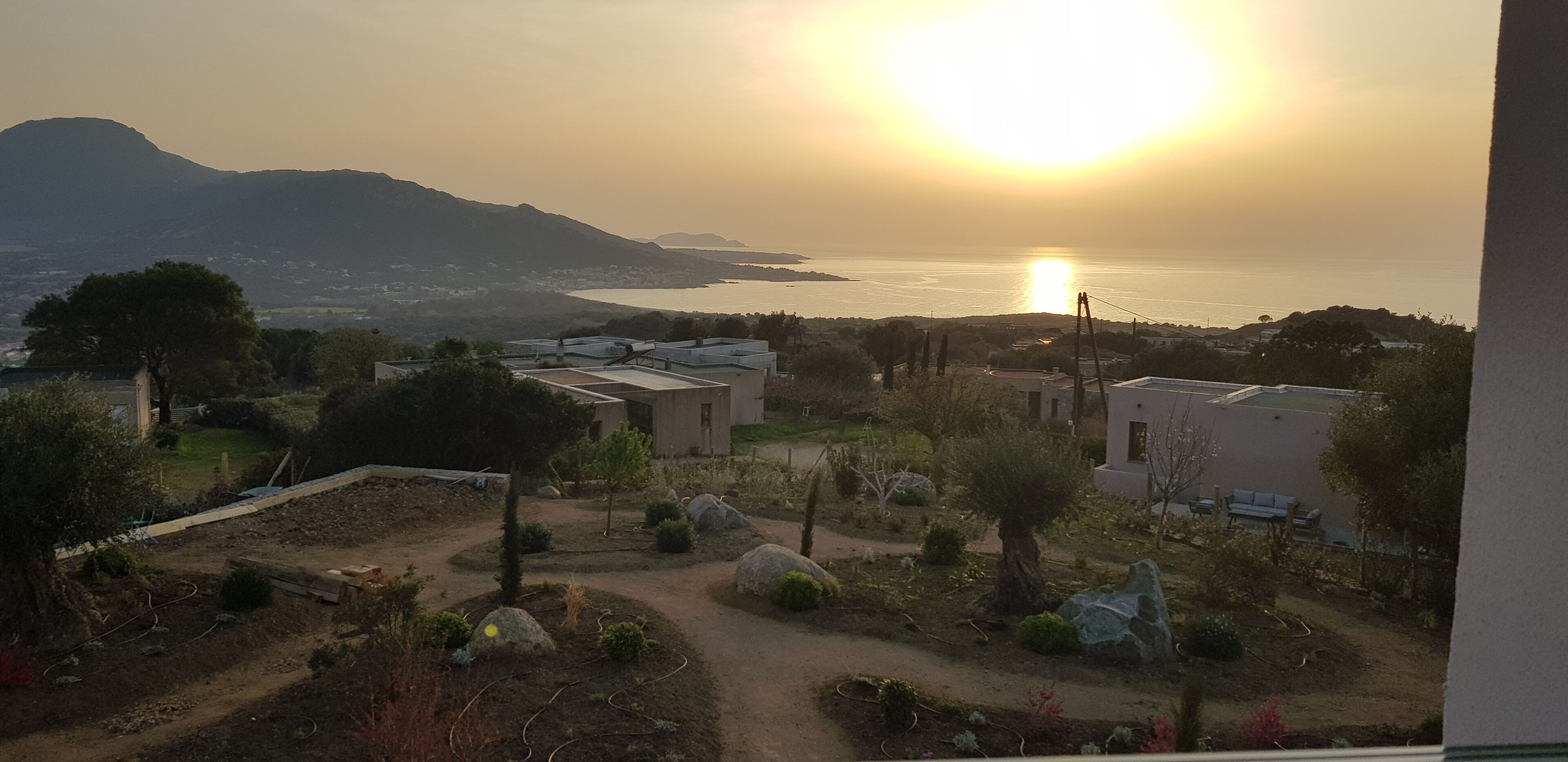 Un paisaje costero con vista al mar y montañas durante el atardecer.