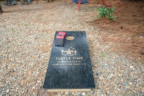 A wooden board with the text "Turtle Time Properties - Slow Down and Enjoy Life" on a gravel surface.