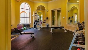 Una palestra con attrezzature per esercizi, specchi e una parete gialla.