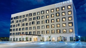 Un moderno edificio de hotel con fachada plana, múltiples ventanas y un letrero que dice 'CITY PLUS EXPRESS'.