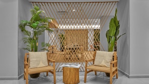 Una habitación con una mesa y sillas de madera, una planta grande y un separador decorativo.