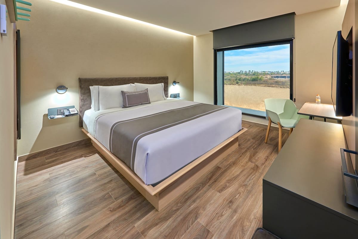 A modern hotel room with a large bed, bedside tables, a desk, and a TV.