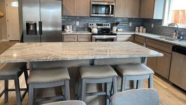 A modern kitchen with a large island, stainless steel appliances, and wooden cabinets. - This house is a 4 bedroom(s), 2 bathrooms, located in Eagle Point, OR. (Eagle Point)
