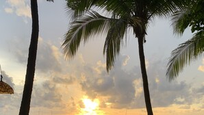 An outdoor seating area with tables and chairs, overlooking a beach with the ocean and a sunset. - PERFECT LUXURY stay steps to the ocean, amazing food, and lots of live music!  (Tamarindo)