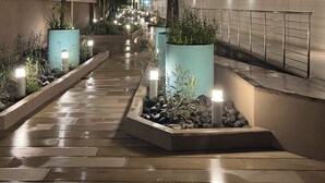 A nighttime walkway with illuminated planters and a modern building facade. - PERFECT LUXURY stay steps to the ocean, amazing food, and lots of live music!  (Tamarindo)