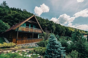 A wooden cabin with a balcony, surrounded by lush greenery and a mountainous backdrop. - Charming chalet for 8 people, 3BD, 2BT, kitchen (Zvolen)