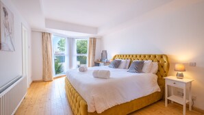 A bedroom with a large bed, a bedside table with a lamp, and a view of the outdoors. - Port Tara Holiday Home, close to Portballintrae Harbour and the Giant's Causeway (Portballintrae, Bushmills)