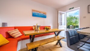 A modern living room with a wooden table, a red sofa, and a black leather bench. - Port Tara Holiday Home, close to Portballintrae Harbour and the Giant's Causeway (Portballintrae, Bushmills)