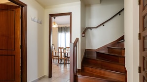 A wooden staircase leading to a dining area with a table and chairs. - Peniche Terrace - Spacious apartment in the center (Peniche)