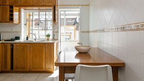A kitchen with wooden cabinets, a white countertop, and a large window. - Peniche Terrace - Spacious apartment in the center (Peniche)