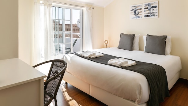 A hotel room with a bed, a desk, and a chair. - Peniche Terrace - Spacious apartment in the center (Peniche)