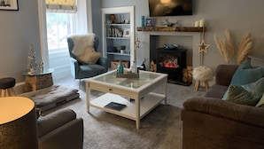 Una sala de estar acogedora con chimenea, estantería, sillón cómodo y televisor de pantalla plana montado en la pared.