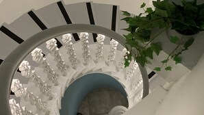 Una escalera de caracol con barandillas blancas y una zona de descanso azul.