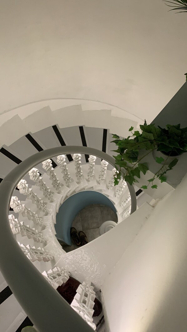 A spiral staircase with white balustrades and a blue landing area.