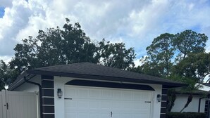 Una casa a un piano con garage, vialetto asfaltato e recinzione bianca.