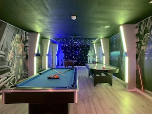 Een pooltafel in een Star Wars-thema kamer, inclusief een muurschildering van een personage en een ruimteschip.