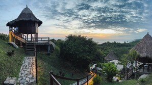 A resort with thatched-roof structures, stone staircases, and a view of the landscape.