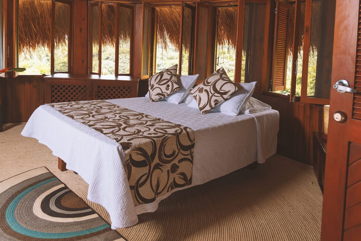 A wooden room with a bed, windows, and a door.