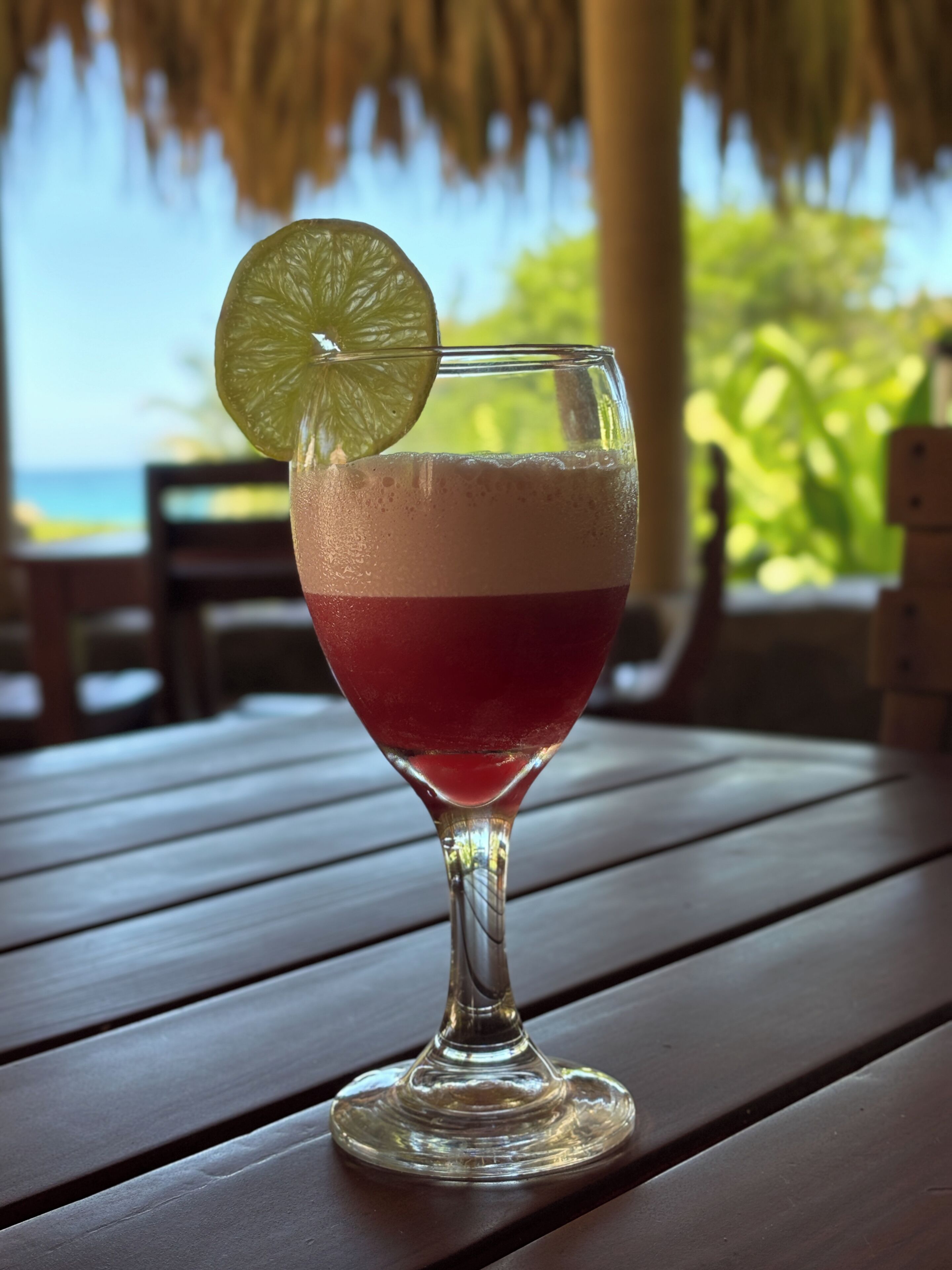 Ein Glas mit einem schichtartigen Getränk auf einer Holztischplatte.