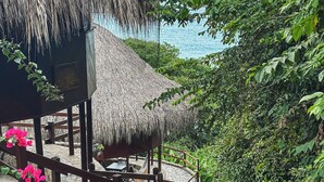 A thatched-roof structure with a stone staircase leading to a wooden deck.