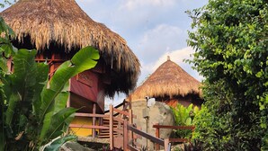 A tropical resort with thatched-roof huts, a wooden staircase, and lush greenery.