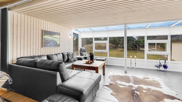 Un salon moderne avec un canapé en cuir, une table basse en bois et une porte vitrée donnant sur un jardin.