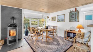 Une pièce chaleureuse avec une cheminée, une table à manger, des chaises et un tapis.