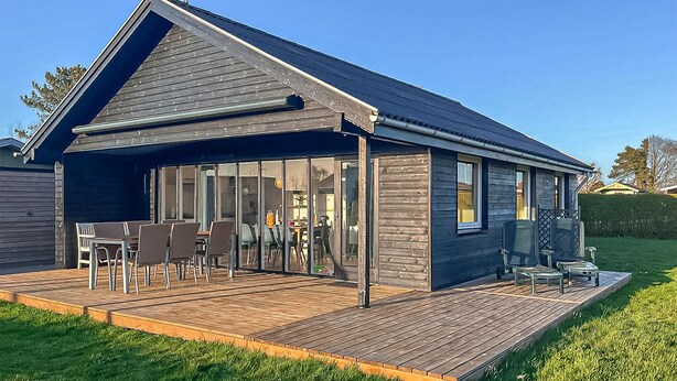 Une maison moderne dotée d’un patio couvert, de grandes fenêtres et d’une terrasse.