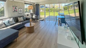 Un salon moderne comprenant un canapé, une table basse et un coin repas avec des chaises.