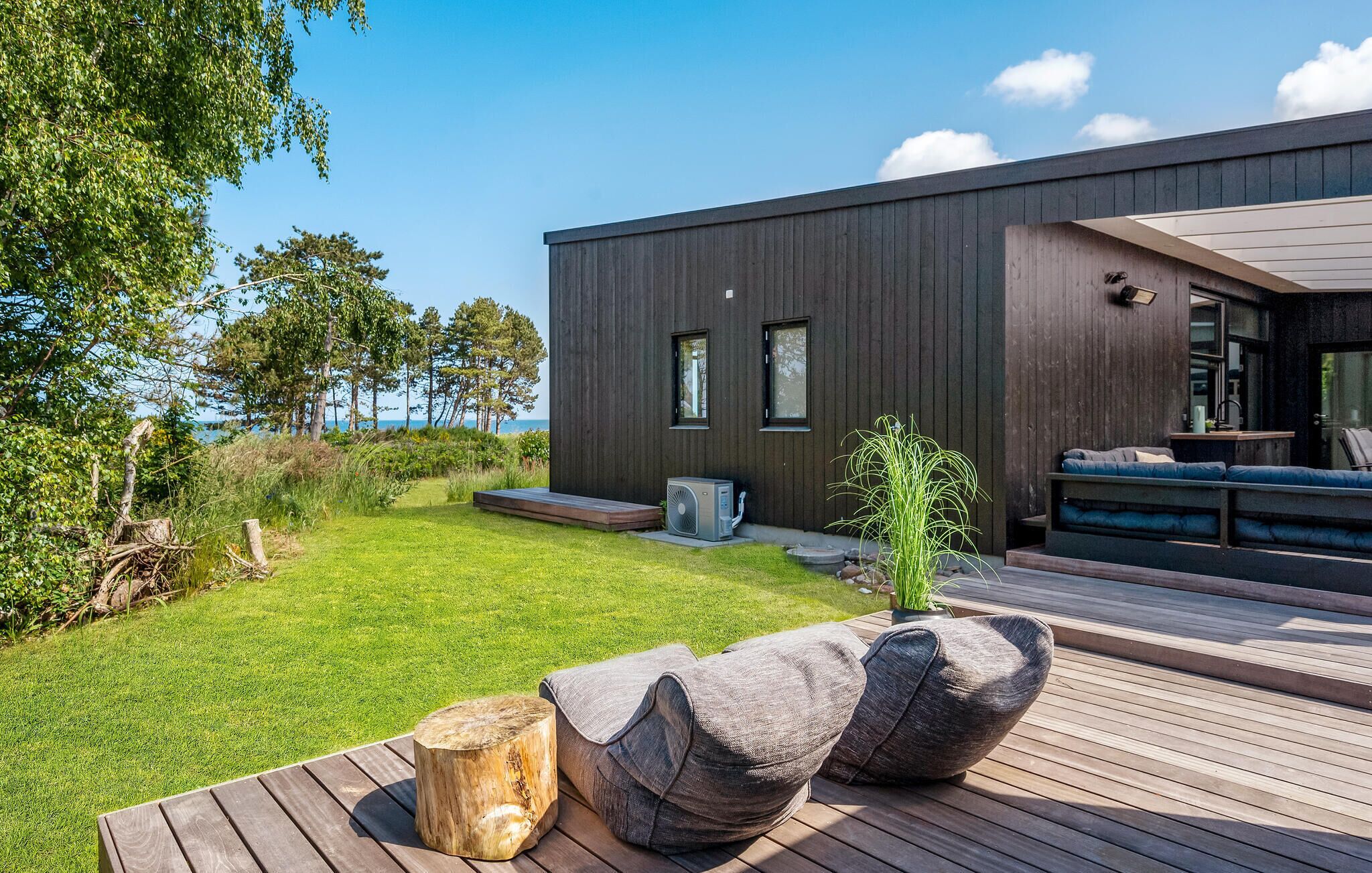 A modern house with a deck, a small garden, and a view of the sea.