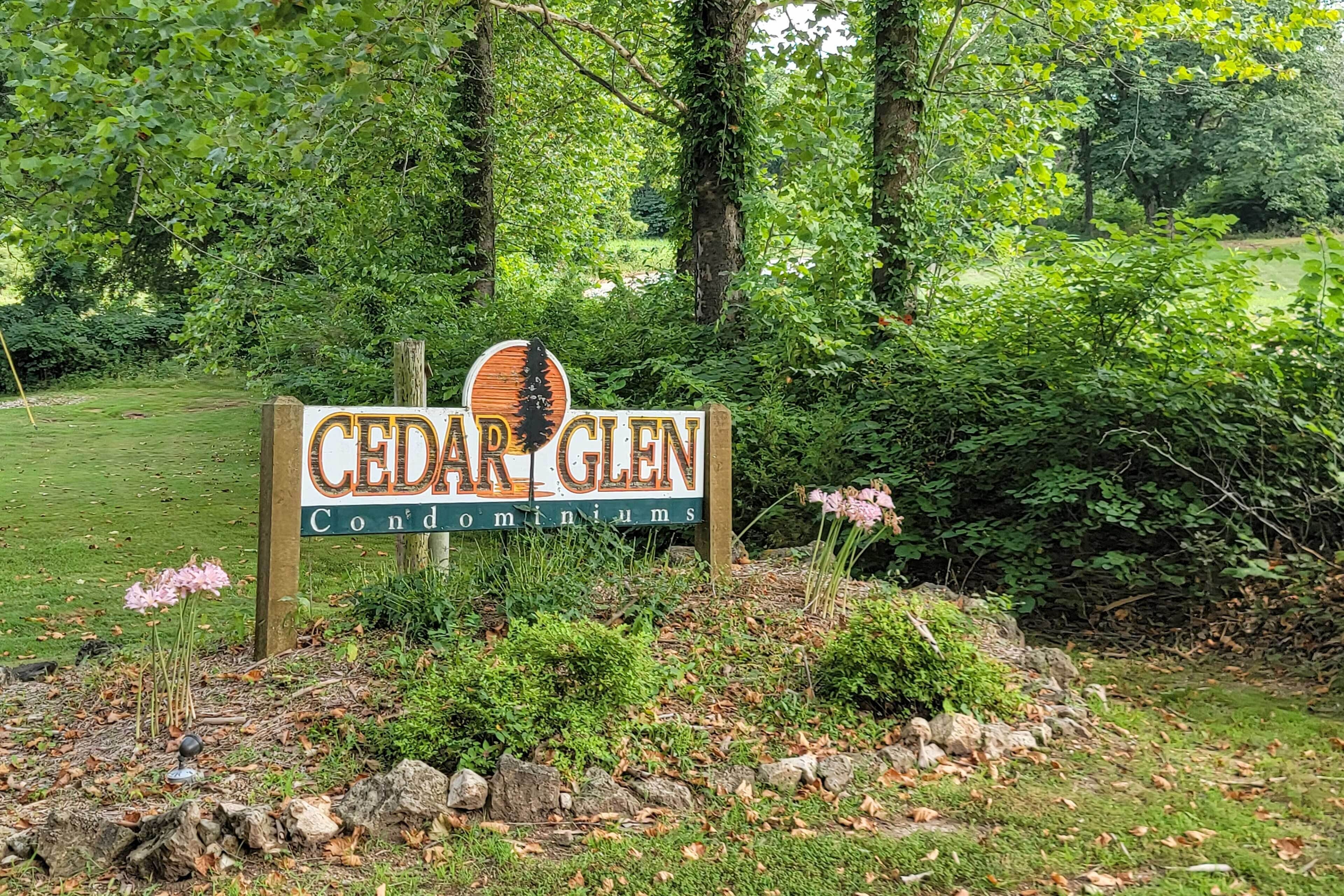 A sign for Cedar Glen Condominiums surrounded by lush greenery.