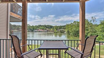 A covered outdoor area with a table and chairs, overlooking a lake and surrounding greenery.