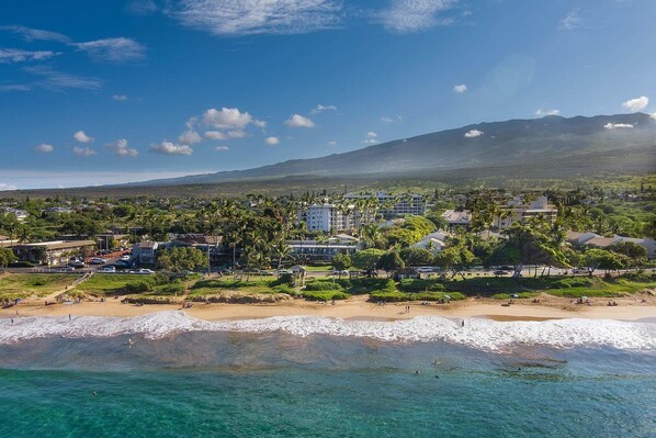 A coastal town with a beach, buildings, and a mountain in the background.