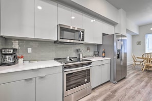 A modern kitchen with stainless steel appliances, grey cabinetry, and a breakfast bar area. - Boise Townhome w/ Rooftop Deck, 2 Mi to Downtown! (Boise)