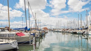Un port de plaisance où sont amarrés de nombreux voiliers, l’eau est calme et le ciel est dégagé.