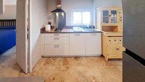 Une cuisine avec des meubles blancs, un fourneau et une fenêtre.