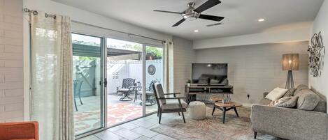 A modern living room with a flat-screen TV, a ceiling fan, and a grey sofa.