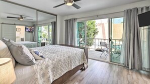 Ein Schlafzimmer mit Bett, Deckenventilator, Fernseher und Balkon mit Tisch und Stühlen.