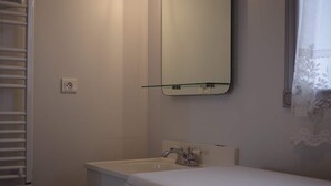 Une salle de bain avec un lavabo blanc, un miroir et un lave-linge.
