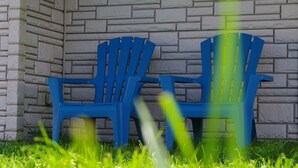Deux chaises en plastique bleu adossées à un mur de pierre.