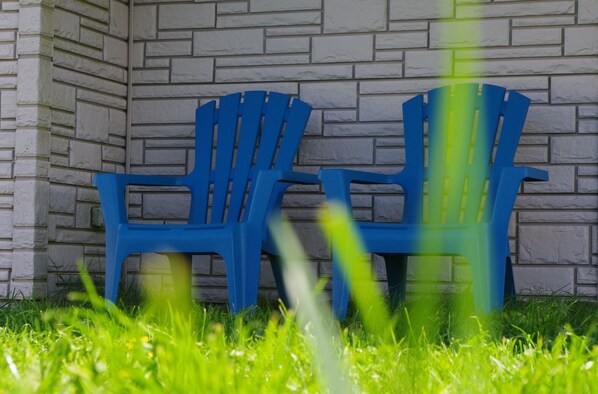 Two blue plastic chairs against a stone wall.